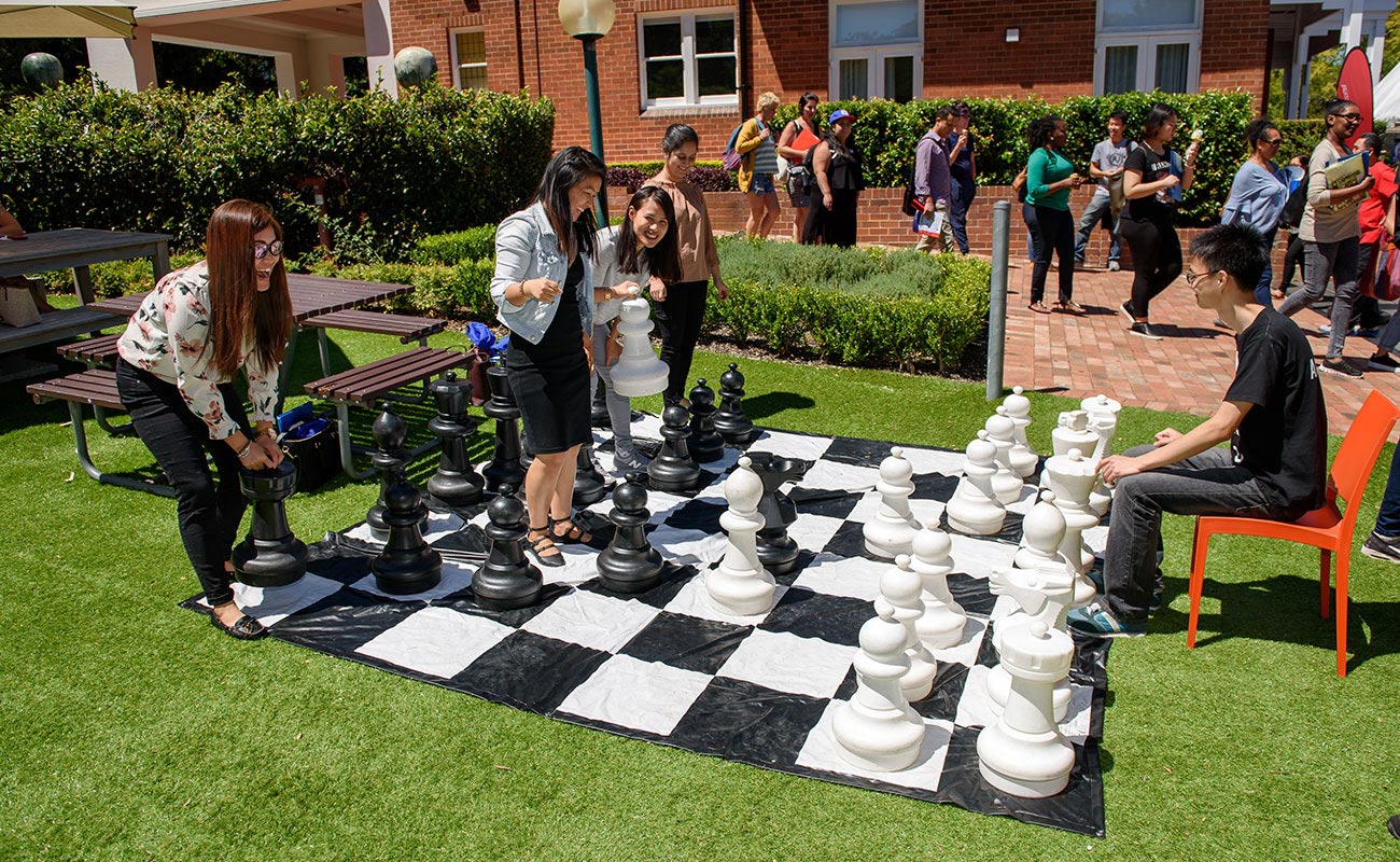 A group of students playing giant chess outside.