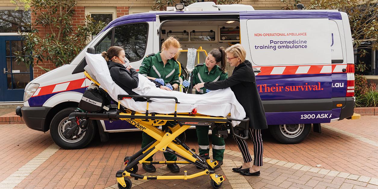 Paramedicine students and instructor standing in front of the ACU training ambulance