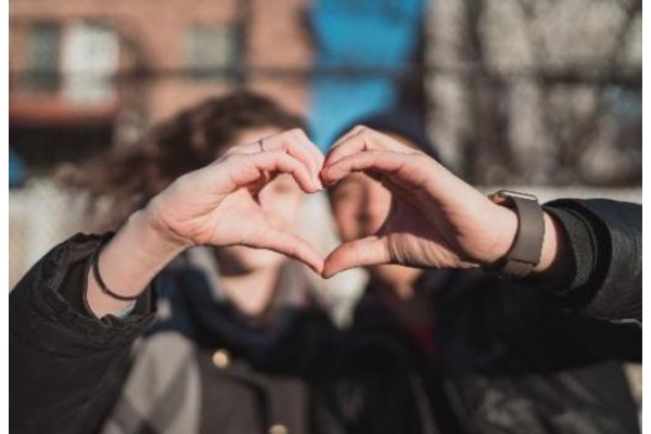 photo of two people holding hand up to make a heart