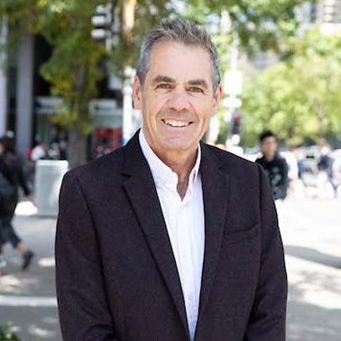 portrait of John Hawley with people walking in the background
