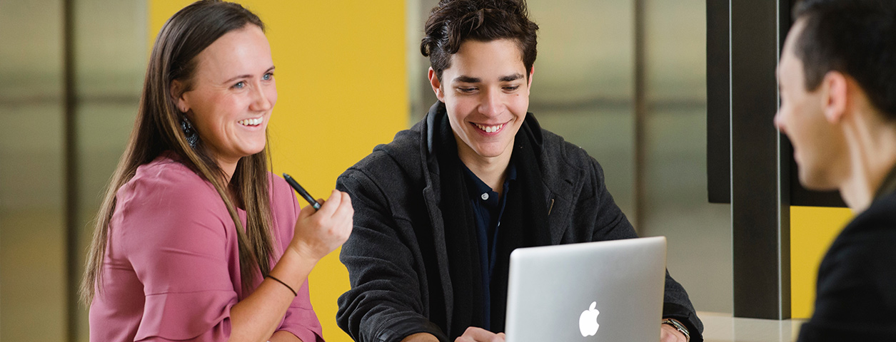 Two students sit in front of a computer.