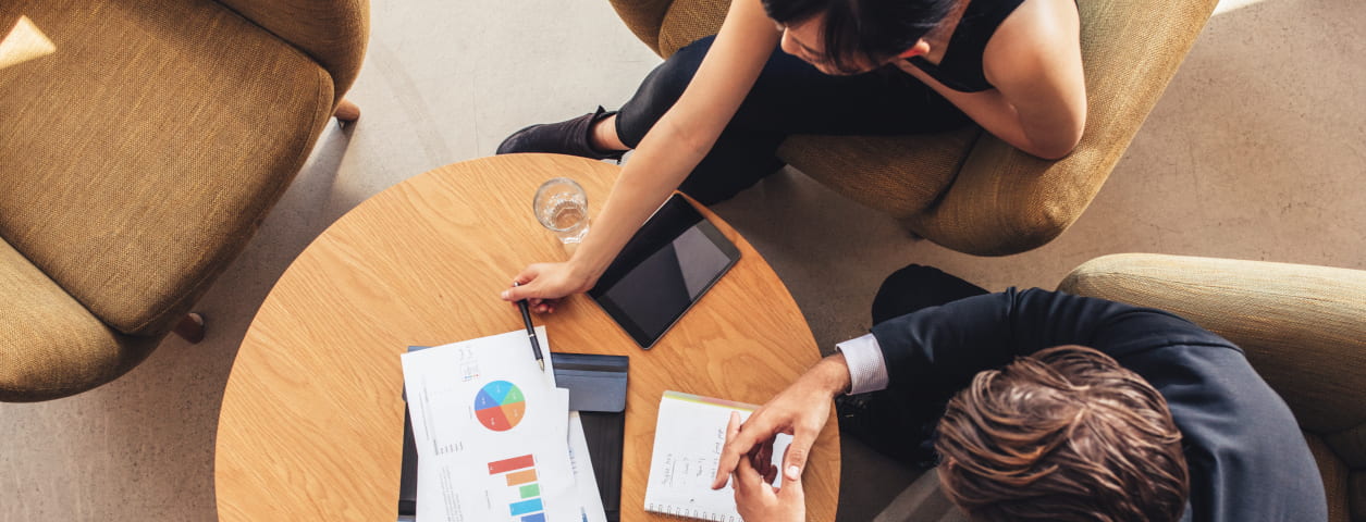 Bird's eye view of two professionals sitting at a meeting table with a business presentation on top