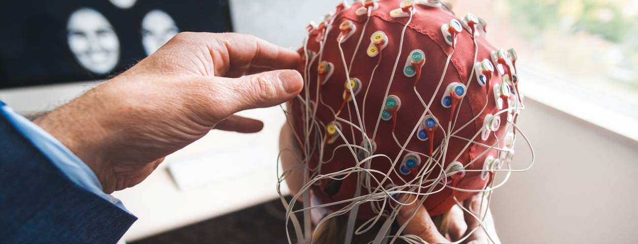 pair of hands fixing a brain sensor device to a patient.
