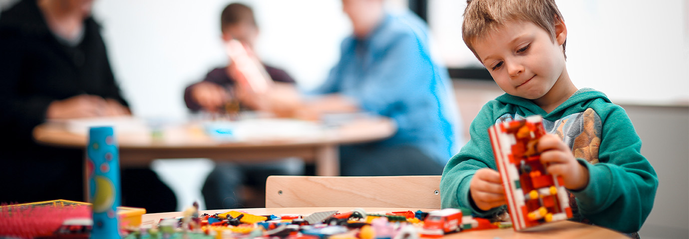 A child sits at a table building  with construction blocks