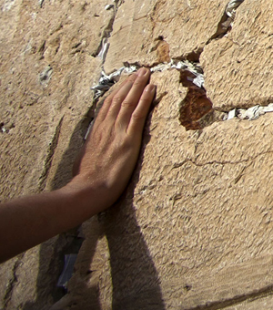 A hand caresses a cracked stone wall