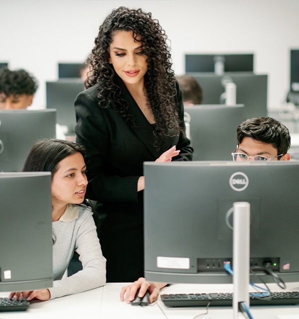 Three people gathered around a computer, smiling and learning