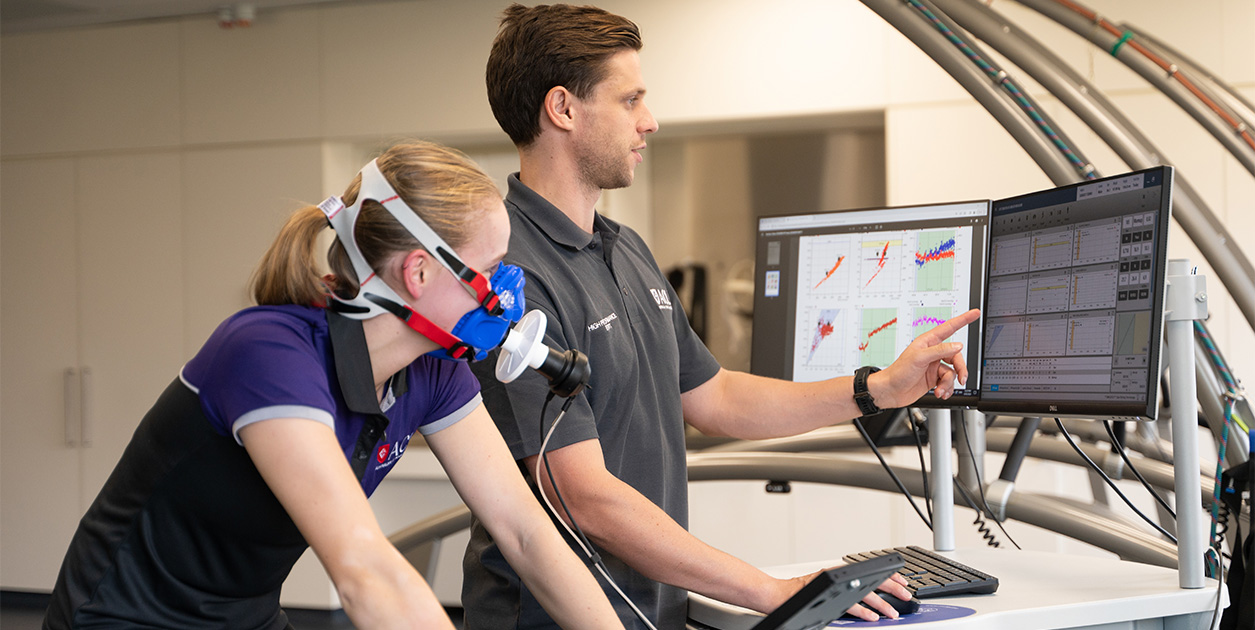 A sport and exercise science student tests an athlete's breathing and is checking the data.