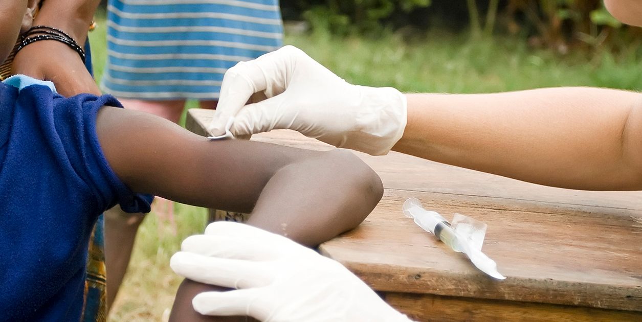 Outside close-up of a child's arm being prepared for an injection