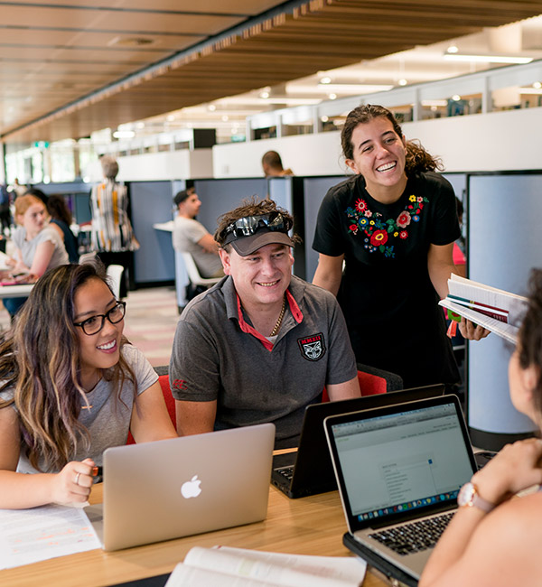 A group of students sit on a table with laptops