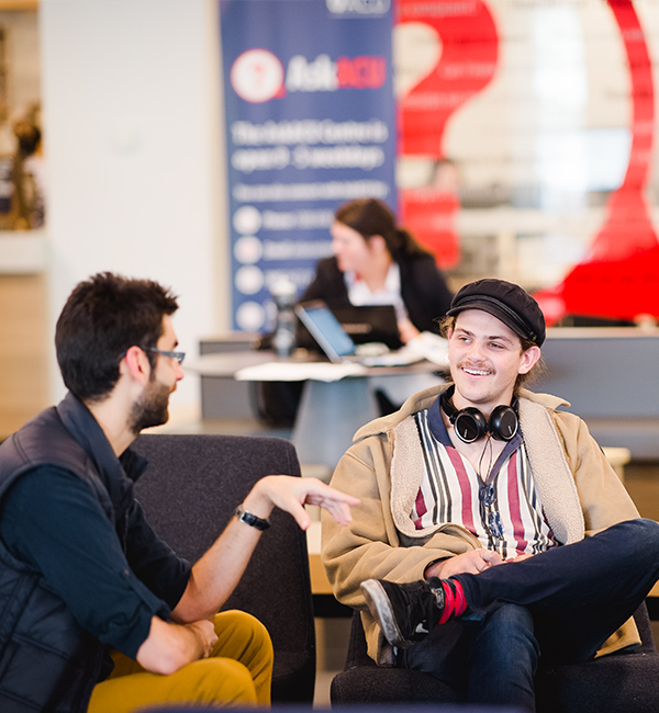 Two men sit on couches talking to each other