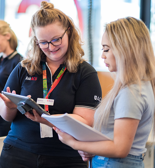 Two girls stand side by side, talking
