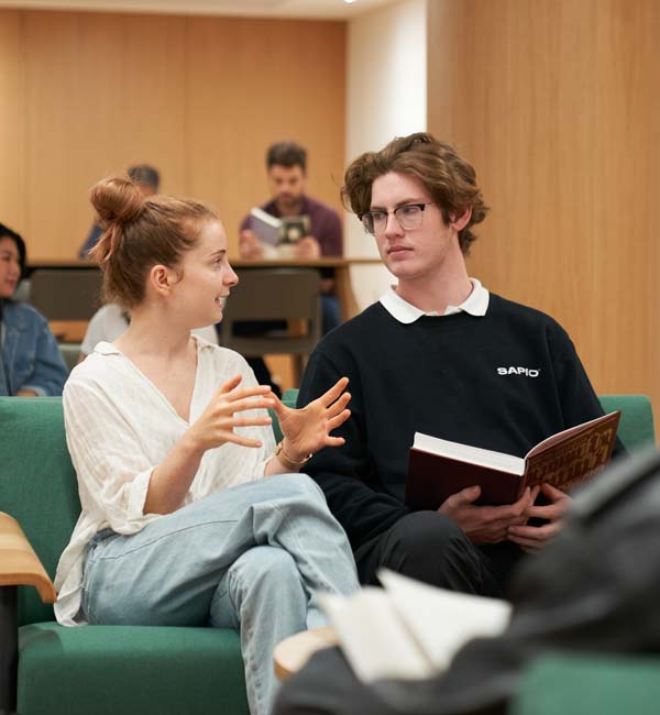 Two students having a discussion in a lecture theatre.