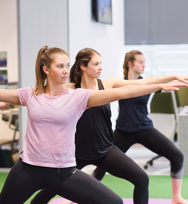 Three women in fitness gear are doing yoga