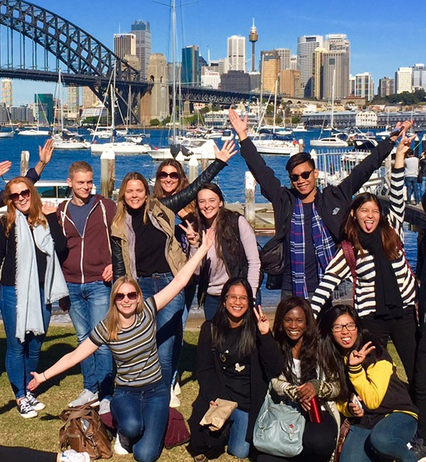 A large group of students poses in front of the Sydney Harbour Bridge