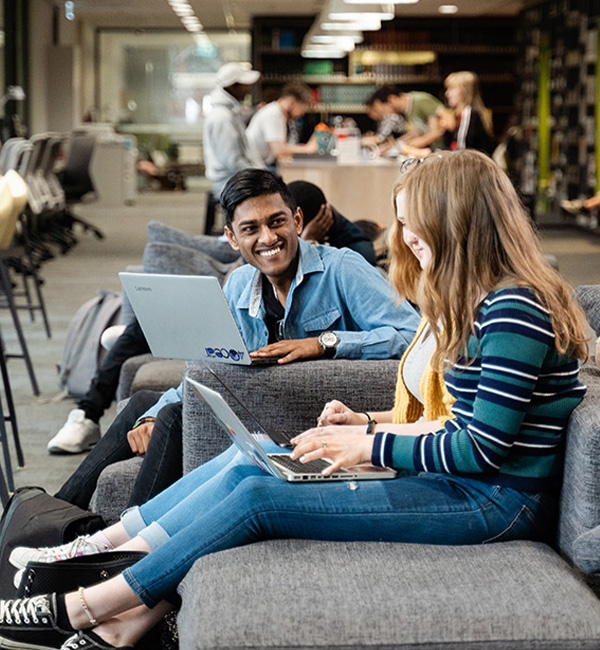ACU mathematics students sitting on campus working on their laptops