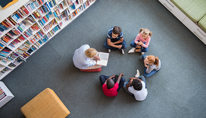A teacher reading to a group of young children in a library