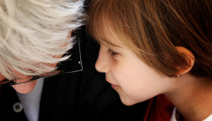 child whispering into adult's ear