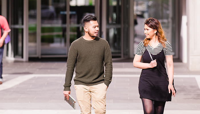 Two students walk through a sunny ACU courtyard
