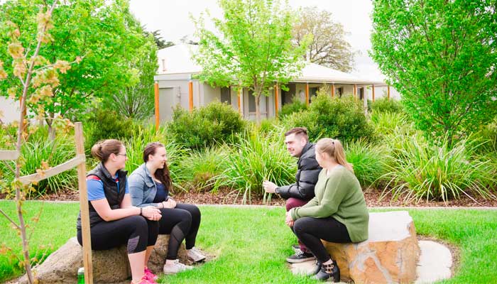 ballarat accommodation 3up Four young students sit on a green lawn, talking