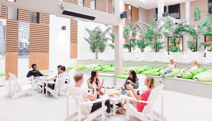 Sydney accomodation 3up Students are sitting around on white outdoor furniture and chatting, relaxed.