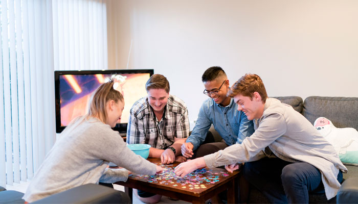 Four jovial students are playing a board game together